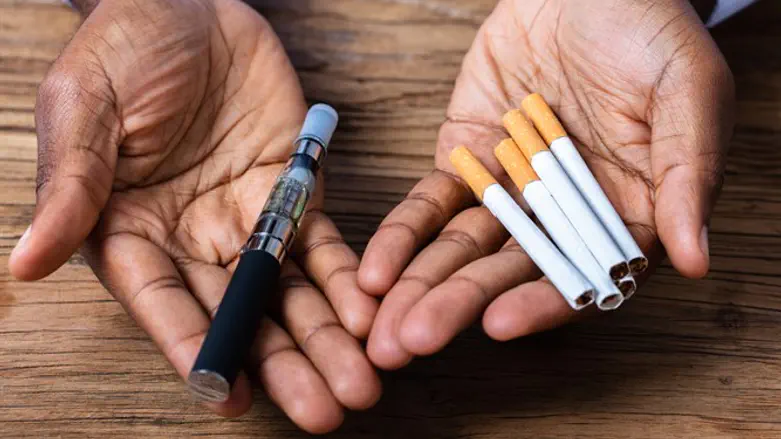 Man holds e-cigarette and regular cigarettes
