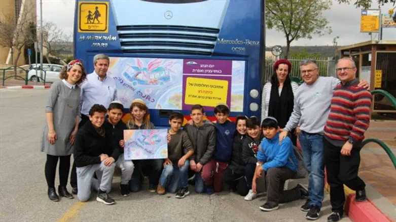 התלמידים עם הכרזה הזוכה המודפסת על האוטובוסים