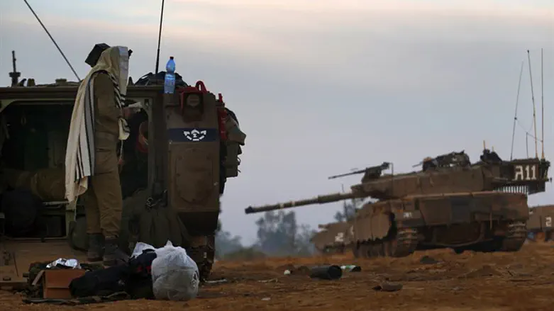 Israeli soldier prays by an APC at the Gaza border