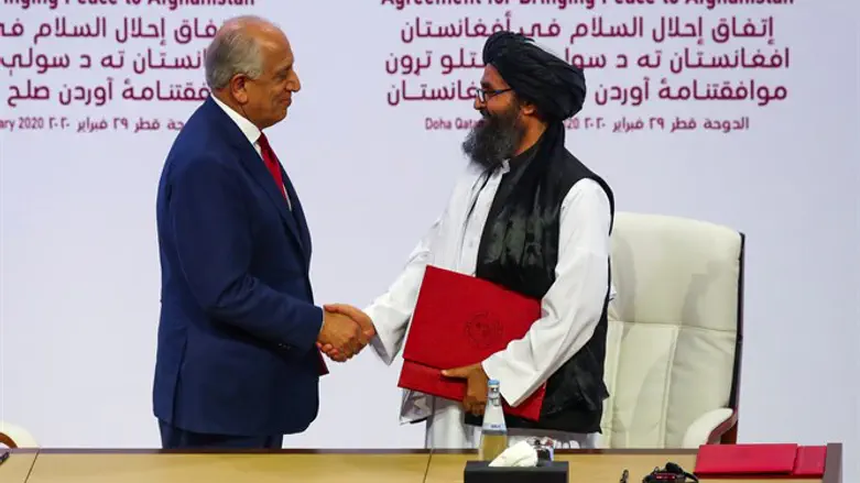 Mullah Abdul Ghani Baradar and Zalmay Khalilzad shake hands after signing the agreement