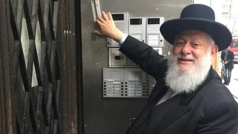הרב יצחק ארנברג עם המזוזה החדשה שהתקין